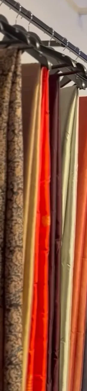 Silks in rust, vermilion and gold hanging on the rail