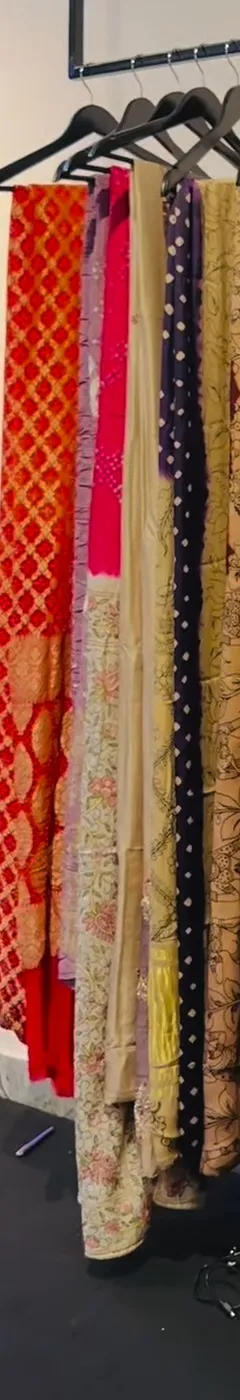 A rail of red, pink and gold sarees, some with woven motifs