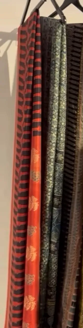 A rust saree with a black leaf print and darker handlooms beside it